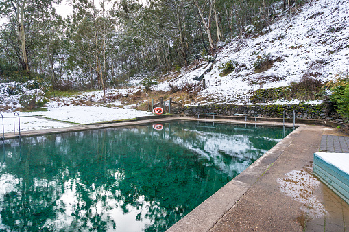 Hot spring pool with crystal clear water and snow covered ground nearby. Yarrangobilly thermal pool, Australia