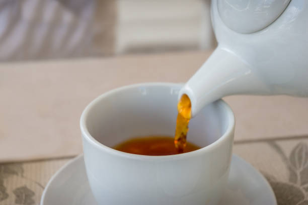 istock Close up of tea pouring in a white tea cup 1171612955