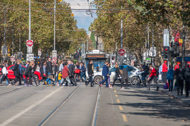 People on pedestrian crossing in Melbourne, Australia Melbourne, Australia - April 29, 2015: People crossing the road on pedestrian crossing with tramway and cars on the background. City infrastructure melbourne street crowd stock pictures, royalty-free photos & images
