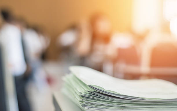 istock Exam answer sheet or application paper blurry view on table in examination room with blur education background of school university students taking exam test writing answer in seat row with stress 1171621980