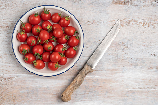 ripe cherry tomatoes and knife on a wooden table with copy space