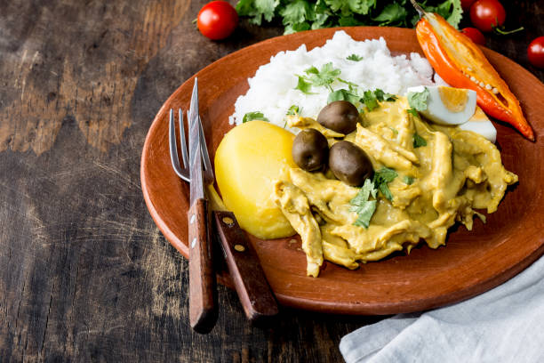 MEXICAN AND PERUVIAN CUISINE. Aji de gallina. Chicken aji de gallina with olives egg and rice on clay plate. Tipical peruvian and mexican dish stock photo