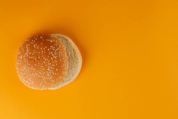 istock Burger bun empty isolated. American food classic round burger bread isolated on a orange background. Grilled burger bun top. 1171643021