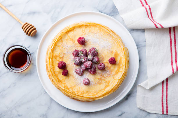 тонкие блинчики с малиной в белой тарелке. мраморный фон. вид сверху. - pancake blini russian cuisine french cuisine стоковые фото и изображения