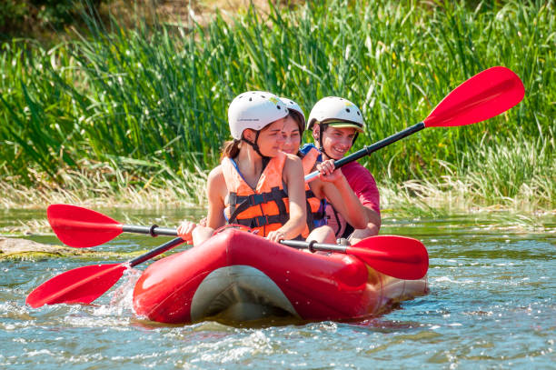 ラフティング旅行。3人の若者が川の膨張式ボートに乗って降りる。人々の誠実な感情。 - family kayaking kayak canoeing ストックフォトと画像