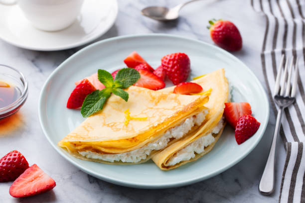 istock Crepes, thin pancakes with fresh strawberry and ricotta, cream cheese stuffing. Marble background. 1171646465
