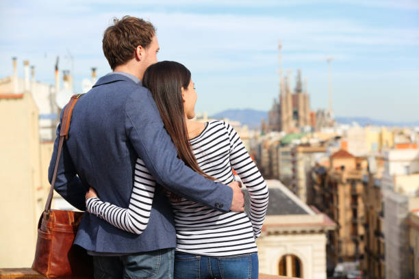 Romantic couple looking at view of Barcelona. Happy lovers enjoying cityscape with famous landmarks. Stylish urban young man and woman on travel in Catalonia, Spain, Europe.