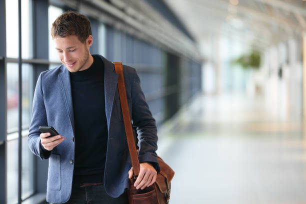 Man on smart phone - young business man in airport Man on smart phone - young business man in airport. Casual urban professional businessman using smartphone smiling happy inside office building or airport. Handsome man wearing suit jacket indoors. office leave stock pictures, royalty-free photos & images