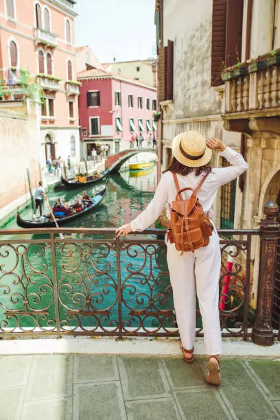 Photo of young pretty woman traveler standing at venice bridge cross canal