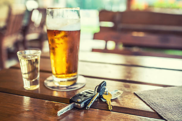 car keys and glass of beer or distillate alcohol on table in pub or restaurant - action alcohol alcoholism bar imagens e fotografias de stock