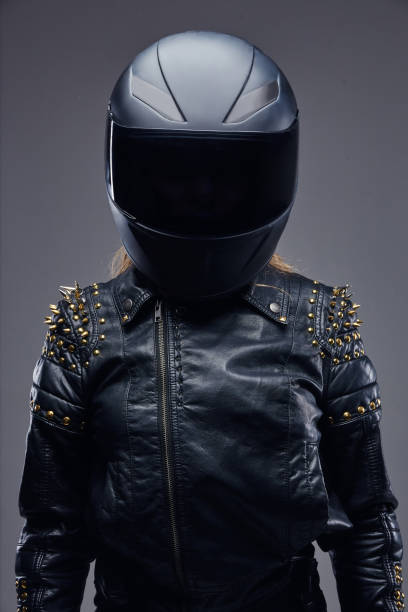 moda, esporte, extremo. retrato de um traje de couro desgastando do racer da menina do motociclista e do capacete protetor em um estúdio em um fundo cinzento. - women jacket leather hooligan - fotografias e filmes do acervo