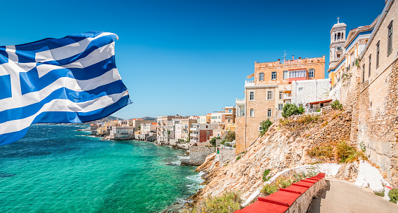 Bright and colorful image of Syros Island with waving Greek National Flag on the side.