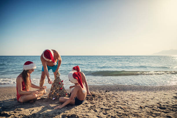 Family building and decorating sand Christmas tree on beach