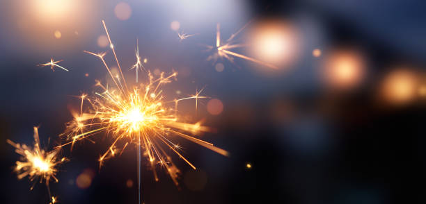 brillante destello ardiente contra fondo de luz bokeh borrosa - sparkler fotografías e imágenes de stock