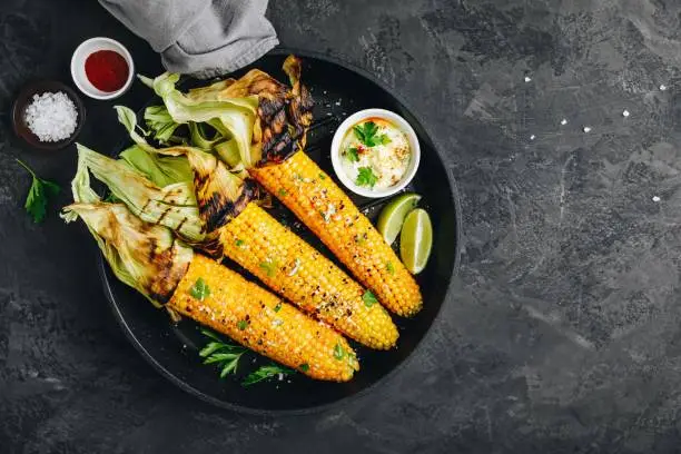 Photo of Roasted or grilled sweet corn cobs with garlic butter and lime.