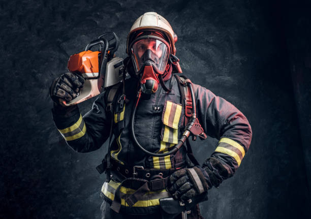 istock Firefighter wearing full protective equipment posing with a chainsaw on his shoulder. Studio photo against a dark textured wall 1171674959