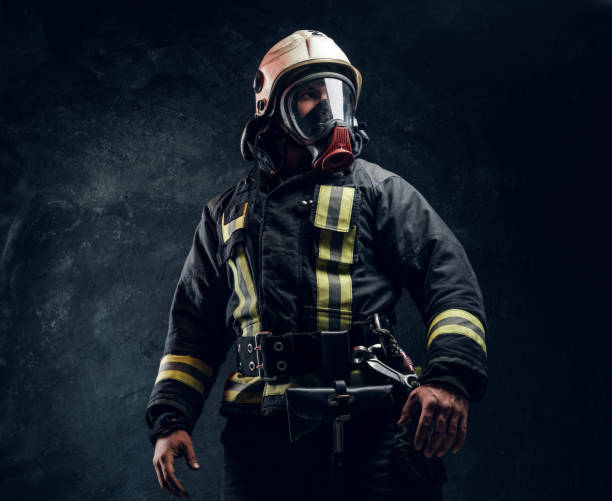 Portrait of a male in full firefighter equipment posing in a dark studio stock photo