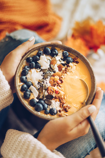 Pumpkin pie smoothie bowl topped with berries, granola, and coconut flakes