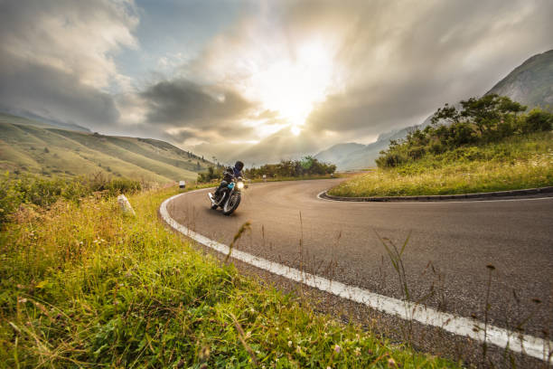 Motorcycle driver riding in Dolomite pass, Italy, Europe. stock photo