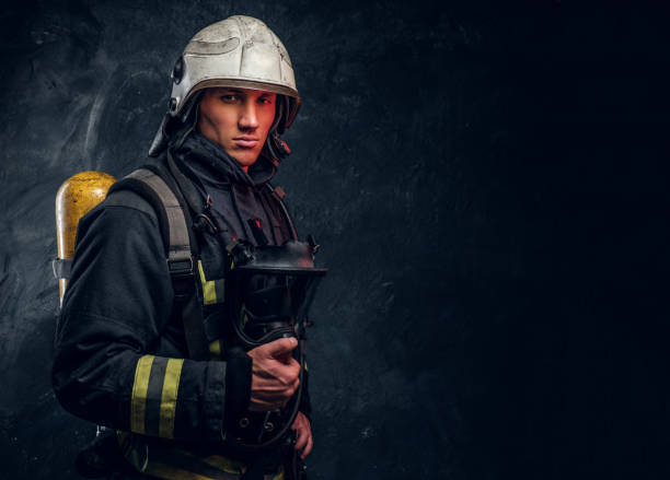 istock Firefighter in full protective equipment holding an oxygen mask and looking at a camera. 1171676396