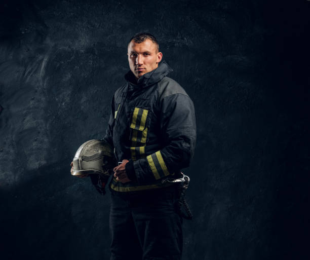 istock Confident fireman in uniform holding a helmet and looks into the camera 1171676550
