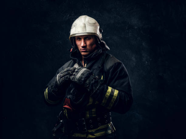 istock Firefighter in uniform and safety helmet posing in a dark studio 1171677883