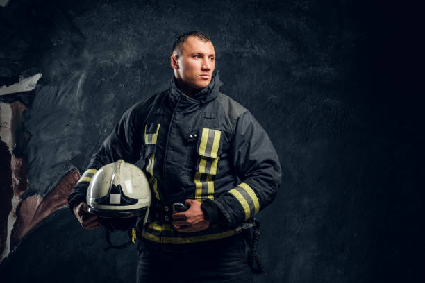 istock Brutal firefighter looks sideways and holds a helmet in his hand 1171678012
