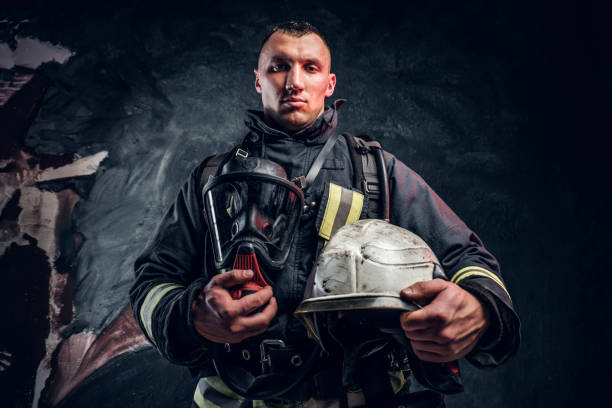 istock A handsome man wearing a fire suit holding an oxygen mask and helmet, looking at a camera. 1171678072
