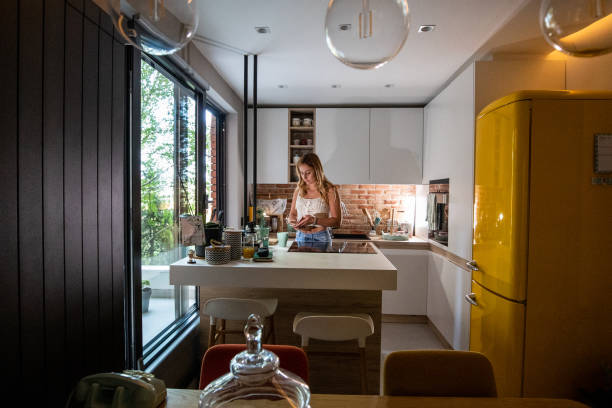 istock Beautiful young woman using her smartphone and drinking coffee in kitchen 1171678137