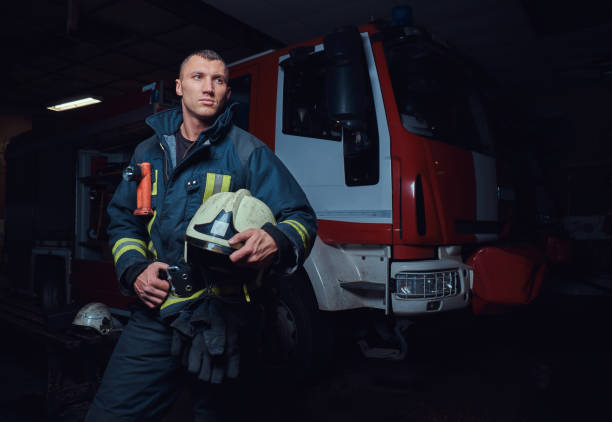 istock Young fireman wearing protective uniform standing next to a fire engine in a garage of a fire department 1171678898