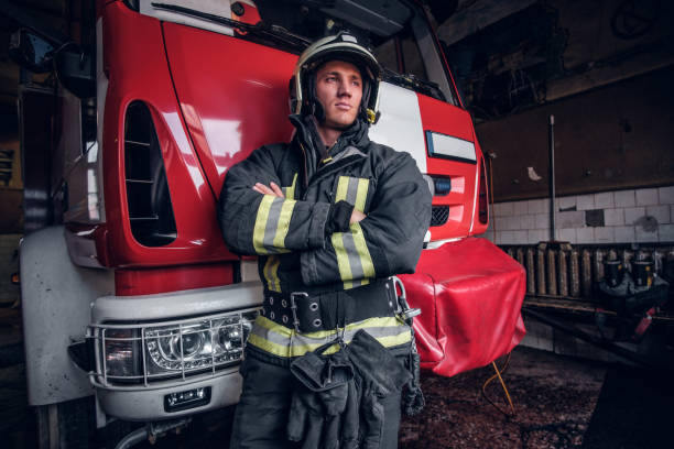 istock Young fireman wearing protective uniform standing next to a fire engine in a garage of a fire department 1171680011