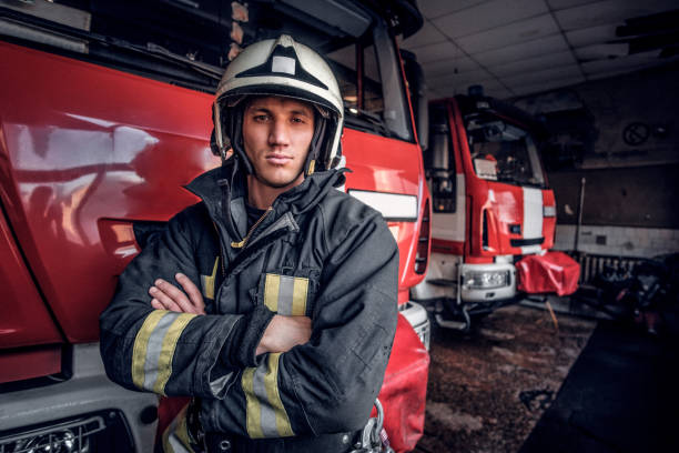 istock A confident fireman wearing protective uniform standing next to a fire engine in a garage of a fire department, crossed arms and looking at a camera 1171680044