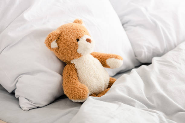 istock Plush teddy bear in bed with white pillows and blanket 1171680066