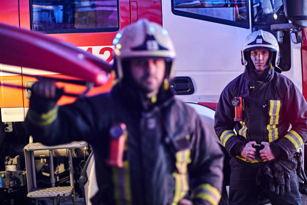 istock Two brave firemen wearing a protective uniform standing next to a fire truck. 1171681556