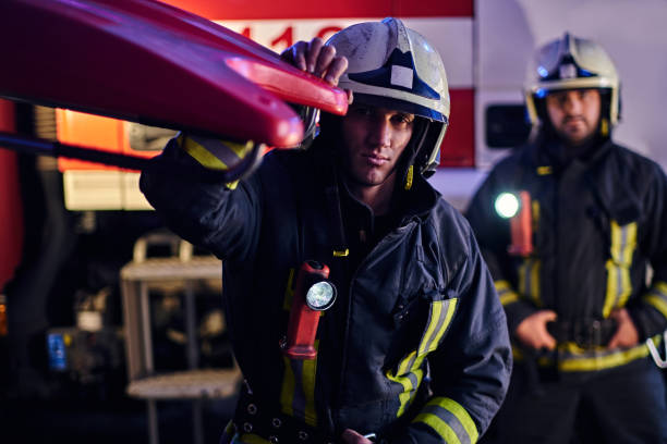 istock Two brave firemen wearing a protective uniform standing next to a fire truck. Arrival on call at night time 1171682367