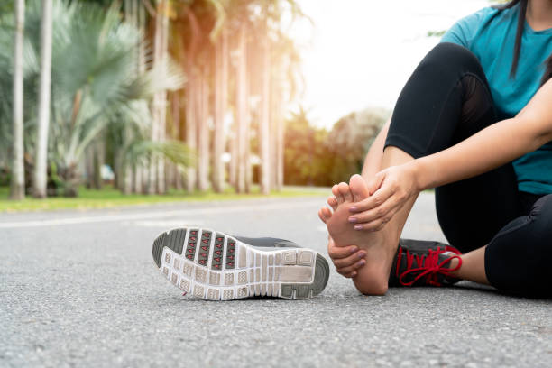 mujer asiática masajeando su pie doloroso mientras hace ejercicio. concepto de ejercicio deportivo y lesiones por ejercicio - sport massaging accident adult fotografías e imágenes de stock