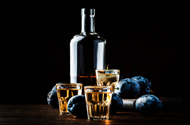 slivovica - plum brandy or plum vodka, hard liquor, strong drink in glasses on old wooden table, fresh plums, copy space - slivovitz imagens e fotografias de stock