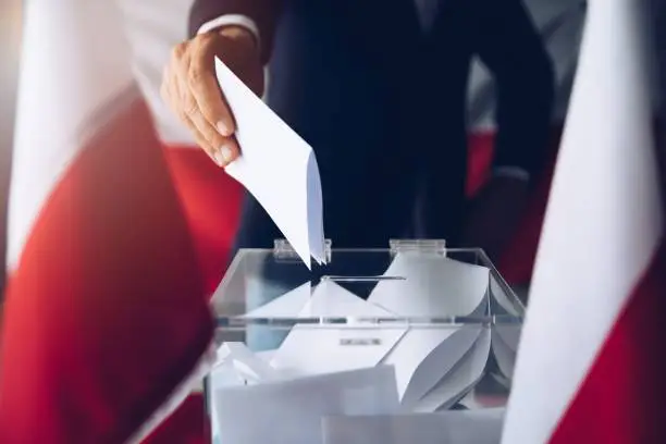 Photo of Man putting his vote do ballot box.