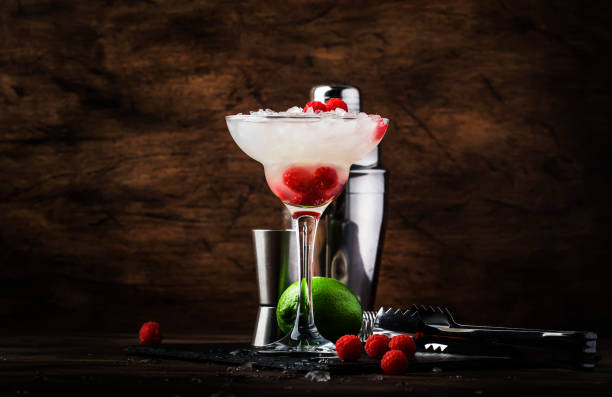 himbeer-daiquiri, alkoholischer cocktail mit weißem rum, limettensaft, himbeeren und zerkleinertem eis aus hohem glas, auf holzstangentheke mit stahlstangenwerkzeugen - crushed ice freshness red lime stock-fotos und bilder