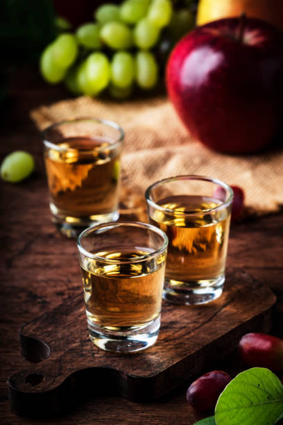 rakija, raki o rakia - bevanda alcolica dura balcanica o brandy da frutta fermentata, vecchio tavolo di legno, natura morta, spazio di copia - vodka hard liquor bottle palinka foto e immagini stock