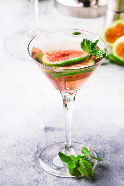 istock Pink fig martini cocktail in shot glass on gray table with bar tools, selective focus 1171685672