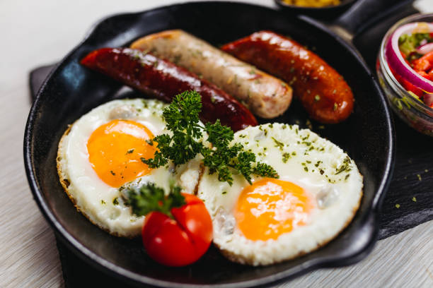 istock Fried eggs sunny side up served with sausage in a cooking pan 1171687358