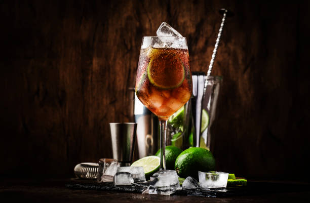 cocktail alcoólico long island com vodka, gin, tequila prata, rum branco, licor, xarope de açúcar, suco de limão, cola e cubos de gelo, vintage bar fundo contador de madeira, foco seletivo - tea island - fotografias e filmes do acervo