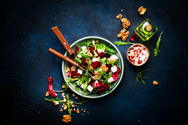 istock Arugula, Beet and cheese salad with fresh radicchio and walnuts on plate with fork, dressing and spices on blue kitchen table background, place for text, top view 1171688474