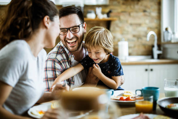 ダイニングテーブルで楽しんでいる若い陽気な家族。 - family indoors happiness laughing ストックフォトと画像