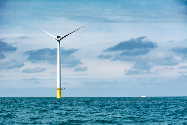 Offshore wind turbine showing immense scale against boat nearby