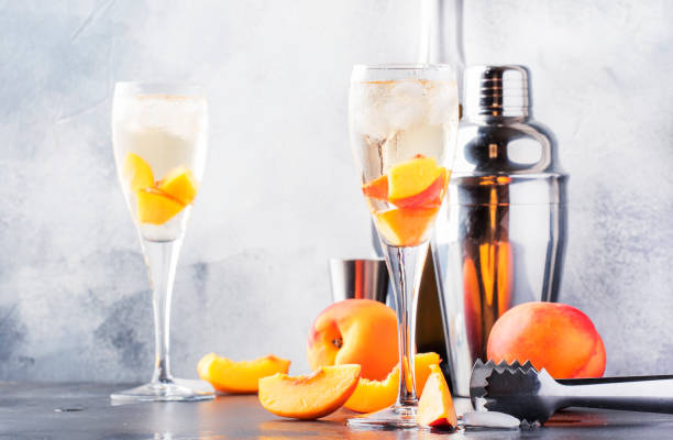 Bellini, alcoholic cocktail with sparkling wine, sugar syrup, lemon juice, peach and ice, gray table background, copy space