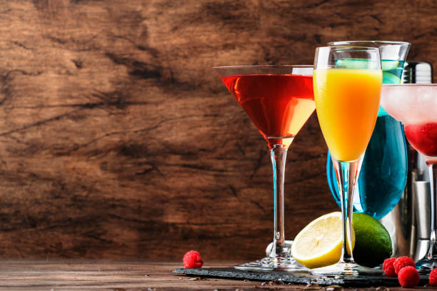istock Colorful summer cocktails. Cold alcoholic beverages and drinks: mimosa, cosmopolitan, raspberry margarita and blue hawaii on wooden table background with bar tools 1171691093