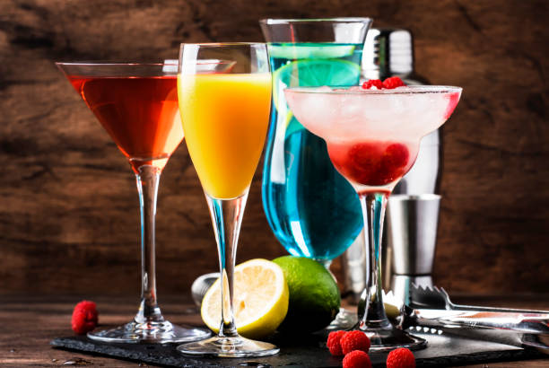 istock Colorful summer cocktails. Cold alcoholic beverages and drinks: mimosa, cosmopolitan, raspberry margarita and blue hawaii on wooden table background with bar tools 1171691122