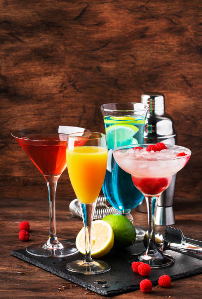 istock Colorful summer cocktails. Cold alcoholic beverages and drinks: mimosa, cosmopolitan, raspberry margarita and blue hawaii on wooden table background with bar tools 1171691140